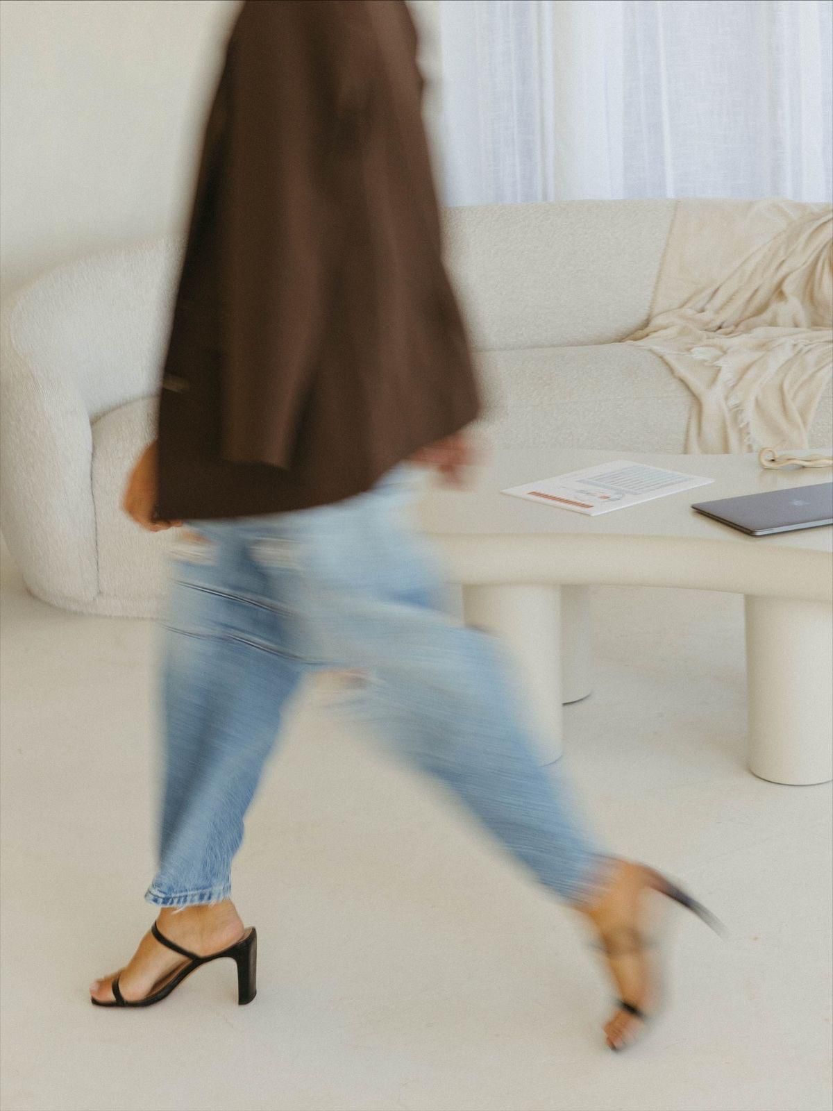 Woman walking past a cream sofa in a bright living room